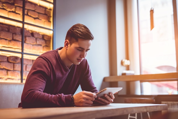 O homem sentado com um tablet no café