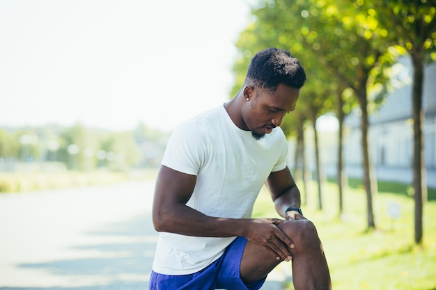 O homem sente fortes dores nos joelhos e nos músculos das pernas após treinar e correr, dor de espasmo