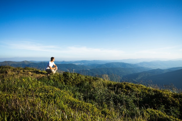 O homem sentou-se no topo da montanha. Inspiração da natureza e viagens, pano de fundo para motivação e letras de conceito