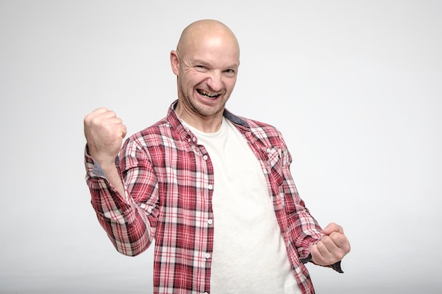 O homem sorridente satisfeito está feliz com a vitória e o sucesso e mostra o punho cerrado com o gesto da mão