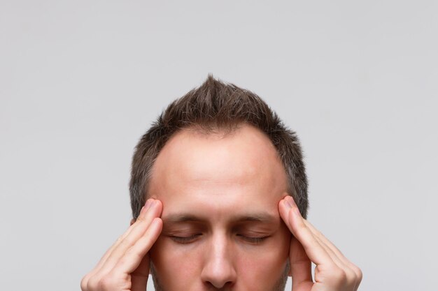 O homem tenta se concentrar, reunir-se com pensamentos, meditando e massageando suas têmporas