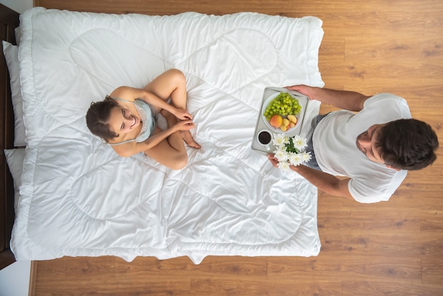 O homem trazendo um café da manhã para uma mulher na cama. vista de cima