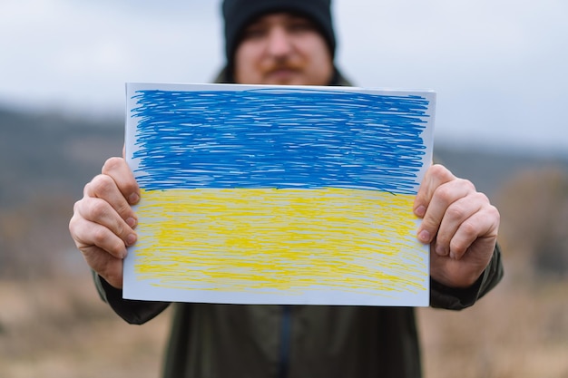 O homem ucraniano segura uma bandeira pintada da guerra da ucrânia da rússia contra a ucrânia