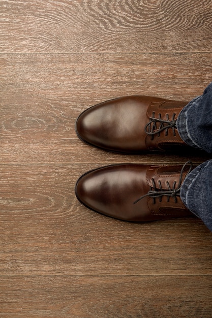 O homem usa sapatos clássicos marrons na farinha de madeira.