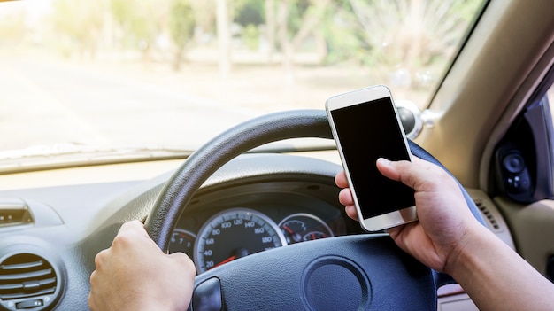 O homem usa um smartphone em seu carro.