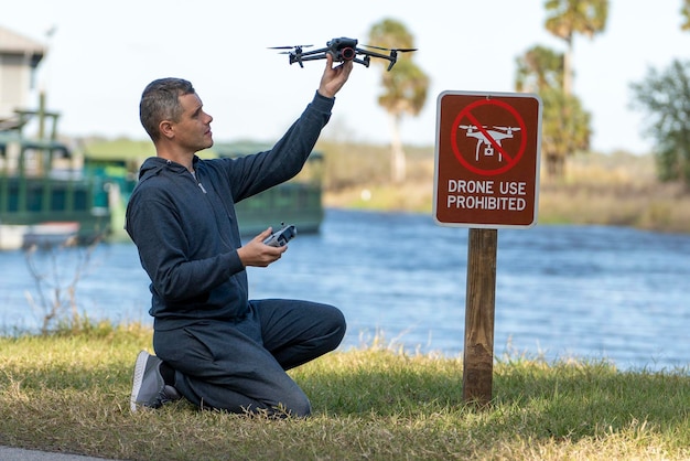 O homem vai pilotar seu quadricóptero em uma área sem drones operador usando ilegalmente seu uas no parque estadual perto do sinal de restrição