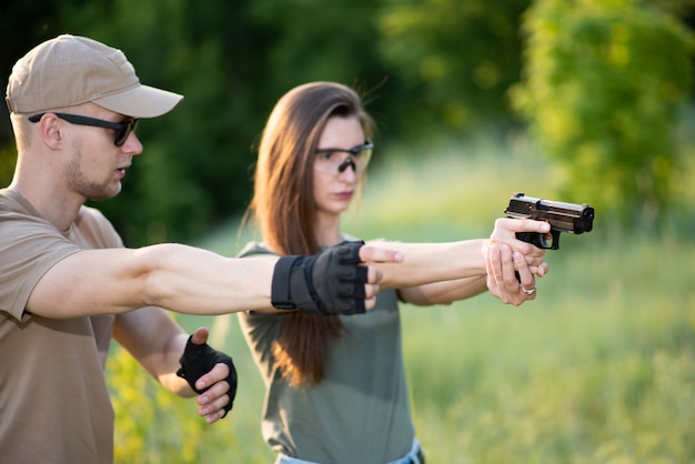 O instrutor ensina a garota a disparar uma pistola ao alcance