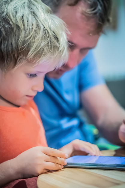 O interesse sério do menino olha no mapa de estudo do telefone inteligente na tela com a ajuda do pai Telefone como educação para o desenvolvimento ou degradação absorve a obsessão do hábito do jogo ao vivo perigo do mundo virtual do conceito de internet