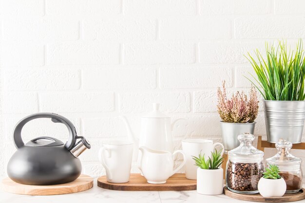 O interior da bancada da cozinha com xícaras de chaleira e várias belas plantas de casa em vasos modernos