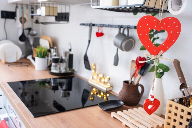 Foto o interior da cozinha na casa é decorado com corações vermelhos para o dia dos namorados decoração na mesa utensílios de fogão humor festivo em um ninho de família