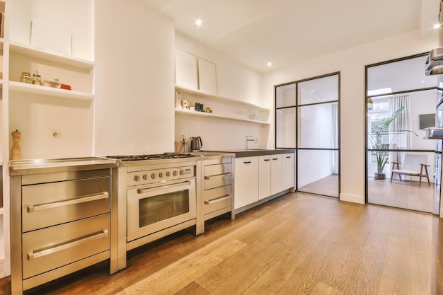 O interior de um estúdio com uma cozinha espaçosa em estilo minimalista em um piso de parquet