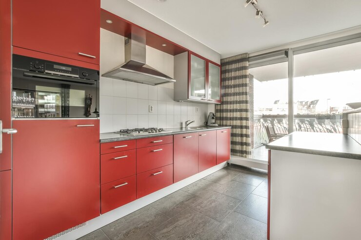 Foto o interior de uma pequena cozinha em tons vermelhos com bancada de mármore em uma casa aconchegante