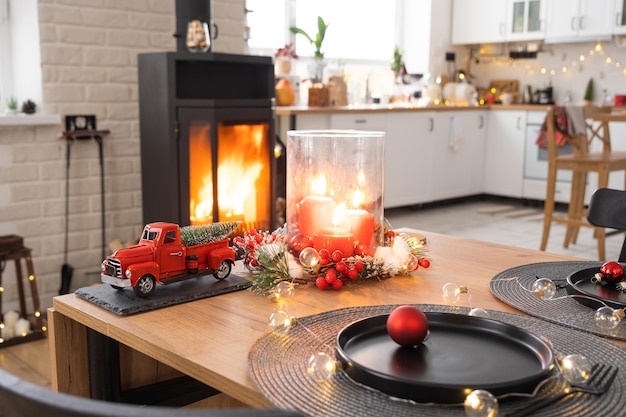 O interior festivo da casa é decorado para o Natal e o Ano Novo em estilo loft com fogão preto lareira Árvore de Natal Sala de estúdio quente com mesa posta queimando madeira aconchegante e aquecimento da casa