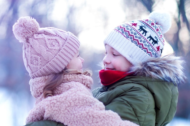 o irmão mais velho abraçou a irmãzinha, olhando-a com ternura e sorrindo. inverno