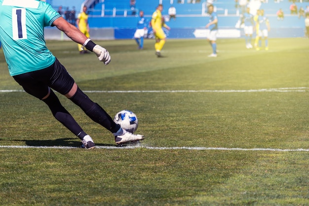 O jogador de futebol bate na bola com a perna direita em uma superfície de grama natural