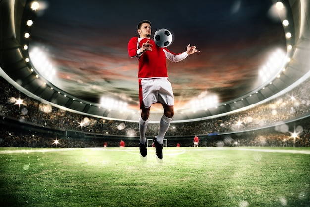 O jogador de futebol defende a bola no campo de um estádio