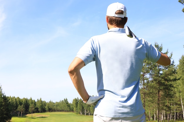 O jogador de golfe acerta um tiro de campo em direção à casa do clube.