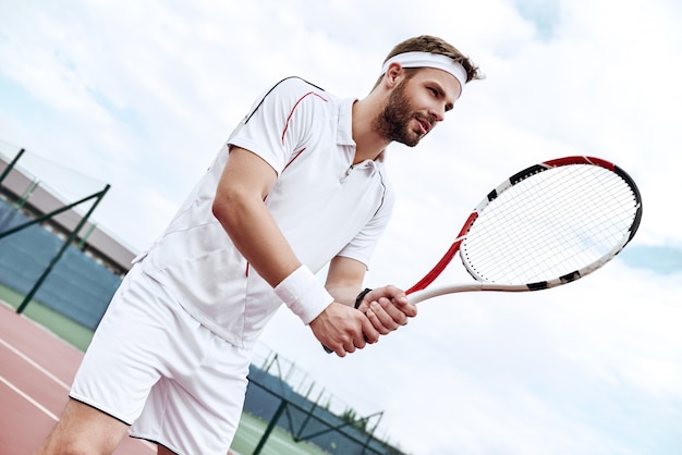 O jogador de tênis profissional está jogando kick tennis em uma quadra de tênis em um dia ensolarado