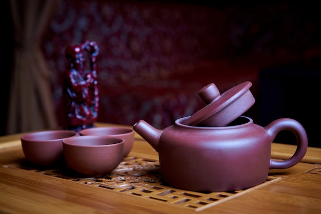 O jogo de chá da argila está em uma placa de madeira.