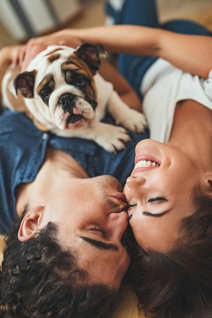 Foto o jovem casal feliz está se mudando para uma nova casa. eles estão deitados no chão com seu cachorrinho depois que trouxeram caixas com coisas para sua nova casa.