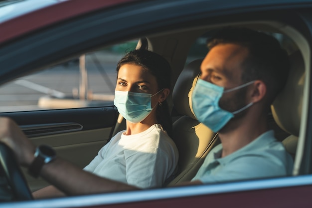 O jovem casal mascarado está sentado no carro