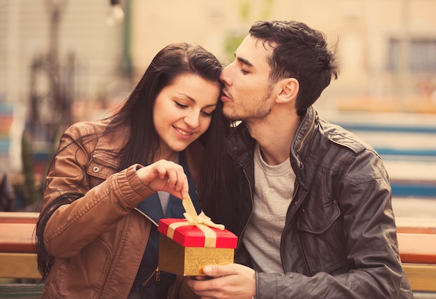 O jovem dá um presente para uma jovem no café e eles estão se beijando.