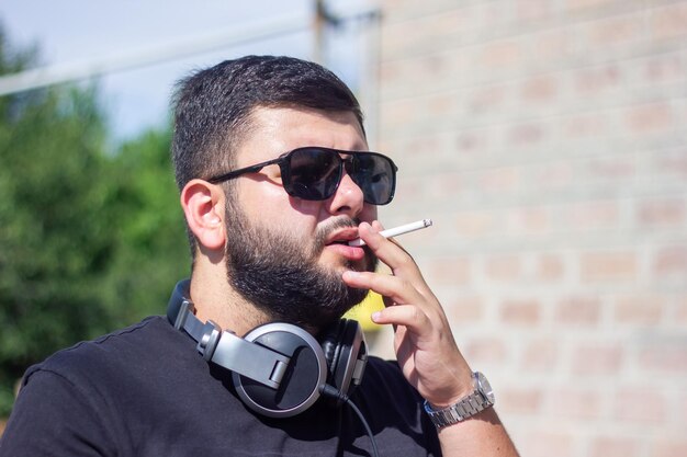 O jovem dj fumando cigarro fumando homem na natureza