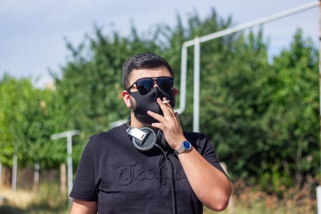 Foto o jovem dj fumando cigarro fumando homem na natureza