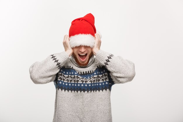 O jovem em camisola gosta de brincar com o chapéu de Santa.