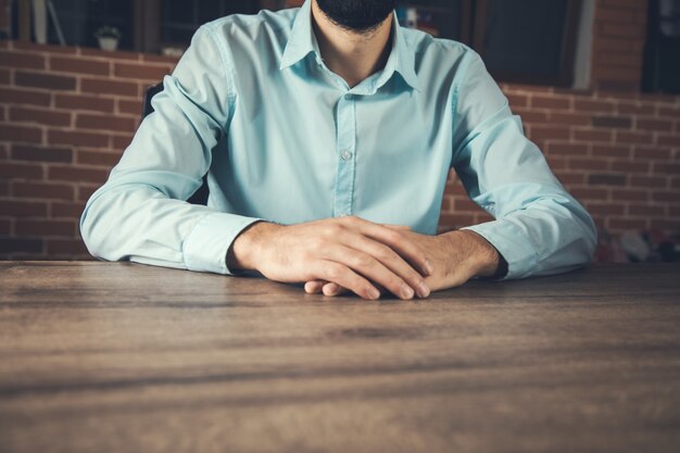 O jovem empresário cruza as mãos na mesa