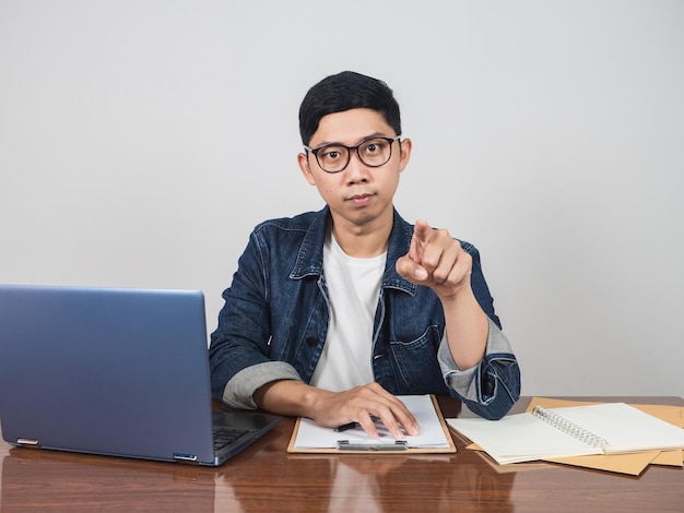 O jovem empresário usa óculos sentados no espaço de trabalho, aponte o dedo para você