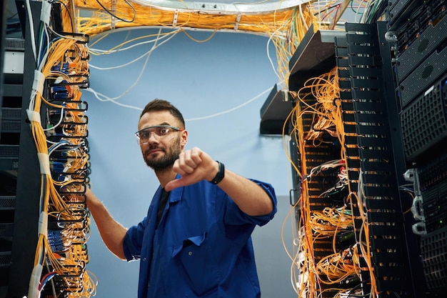 Foto o jovem está a trabalhar com equipamentos de internet e fios na sala do servidor.