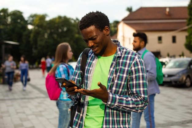 O jovem estudante africano usa navegação em um smartphone