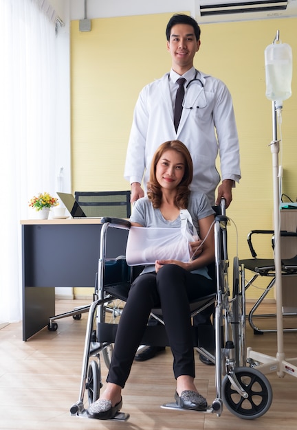 O jovem médico incentivou a paciente do sexo feminino no braço quebrado e na cadeira de rodas.