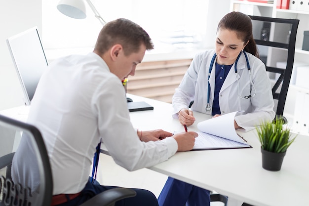 Foto o jovem no consultório do médico assina os documentos