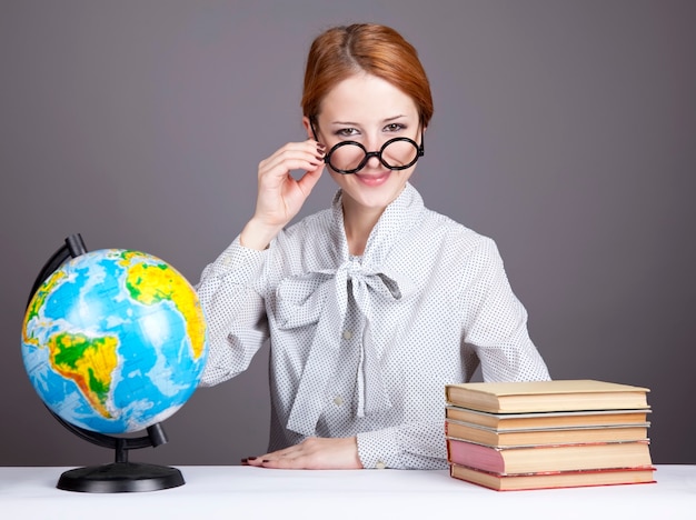 O jovem professor de óculos com livros e globo.