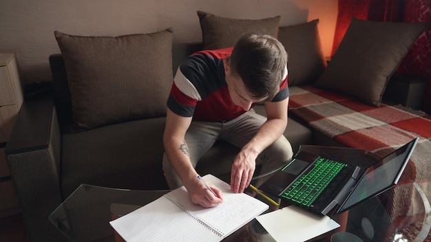 O jovem trabalha em casa, trabalho remoto, preenchendo a papelada