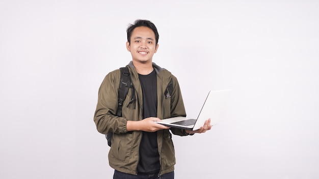 O jovem vestindo uma bolsa em um espaço em branco com um laptop