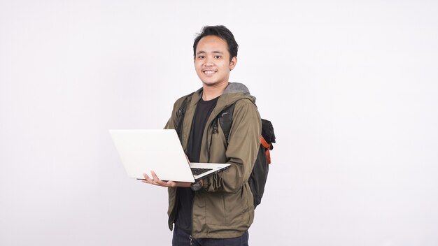 O jovem vestindo uma bolsa em um espaço em branco com um laptop