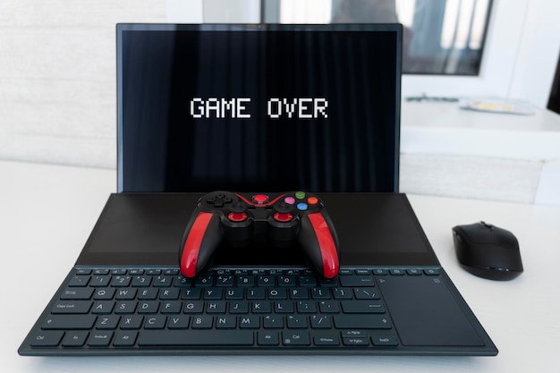 O joystick do console de jogos é preto e vermelho e o conceito de laptop da indústria de jogos e um divertido passatempo doméstico