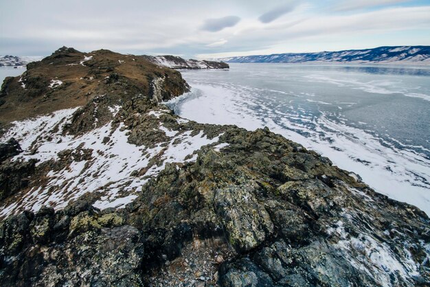 O Lago Baikal é um dia gelado de inverno. O maior lago de água doce. O Lago Baikal está coberto de gelo e neve, forte frio e geada, gelo azul claro e espesso. Pingentes de gelo estão pendurados nas rochas. Herança de lugar incrível