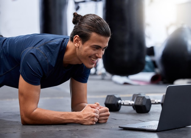 O laptop de exercícios e o personal trainer fazem um vídeo de treino virtual na Internet ou assistem a um tutorial para fitness Criador de conteúdo ou influenciador na academia para treinamento de flexão ou prancha on-line