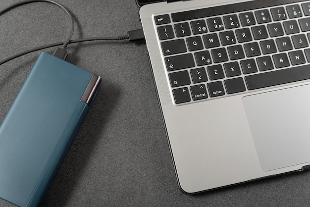 O laptop é carregado pelo powerbank O laptop da vista superior é conectado por cabo a uma bateria externa