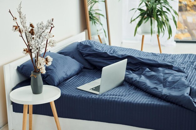 O laptop está na cama Interior e design de um belo quarto moderno durante o dia