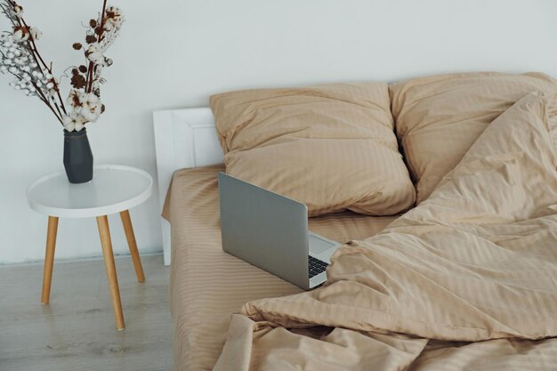 O laptop está na cama Interior e design de um belo quarto moderno durante o dia