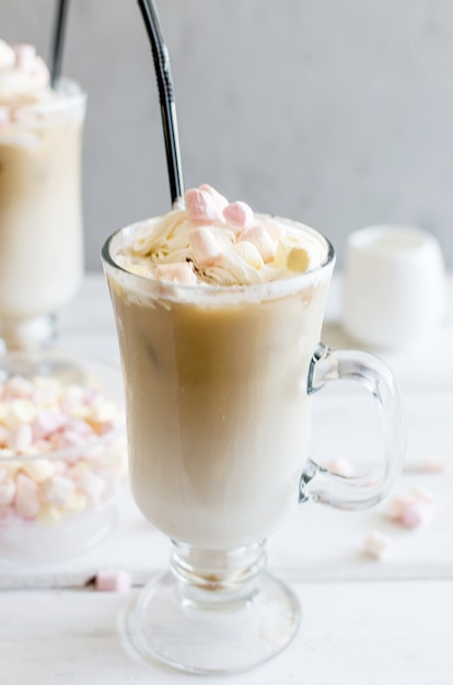 O leite é derramado em um copo com cubos de gelo de café, café gelado