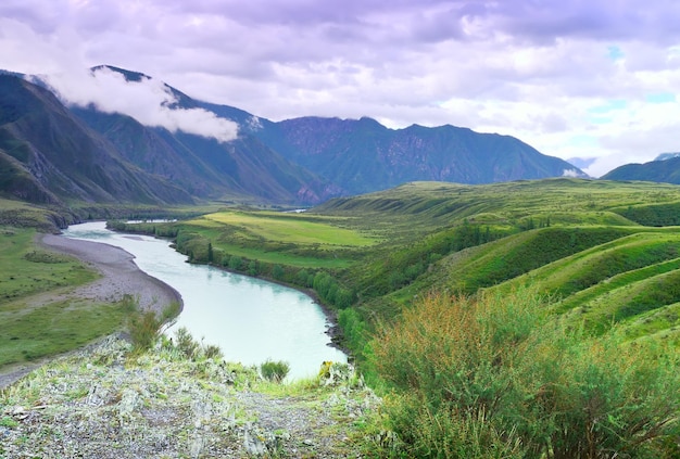 O leito de um rio de montanha no contexto de rochas sob as nuvens Sibéria Rússia