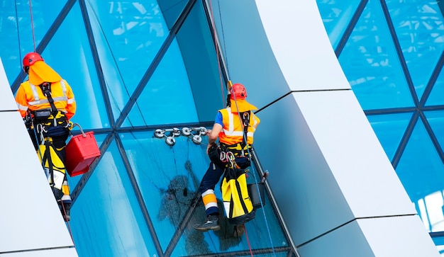 O limpador de janelas trabalhando em um arranha-céu moderno de fachada de vidro