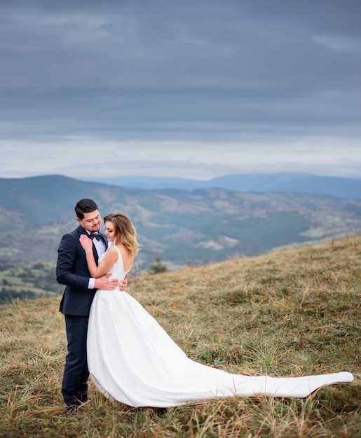 O lindo casal apaixonado abraçando e permanente no campo