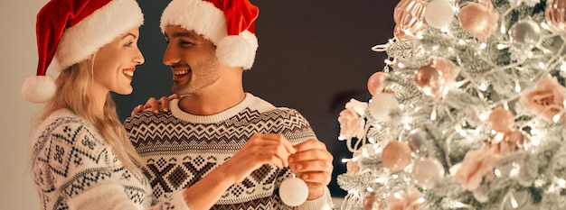 Foto o lindo casal decorando a árvore de natal